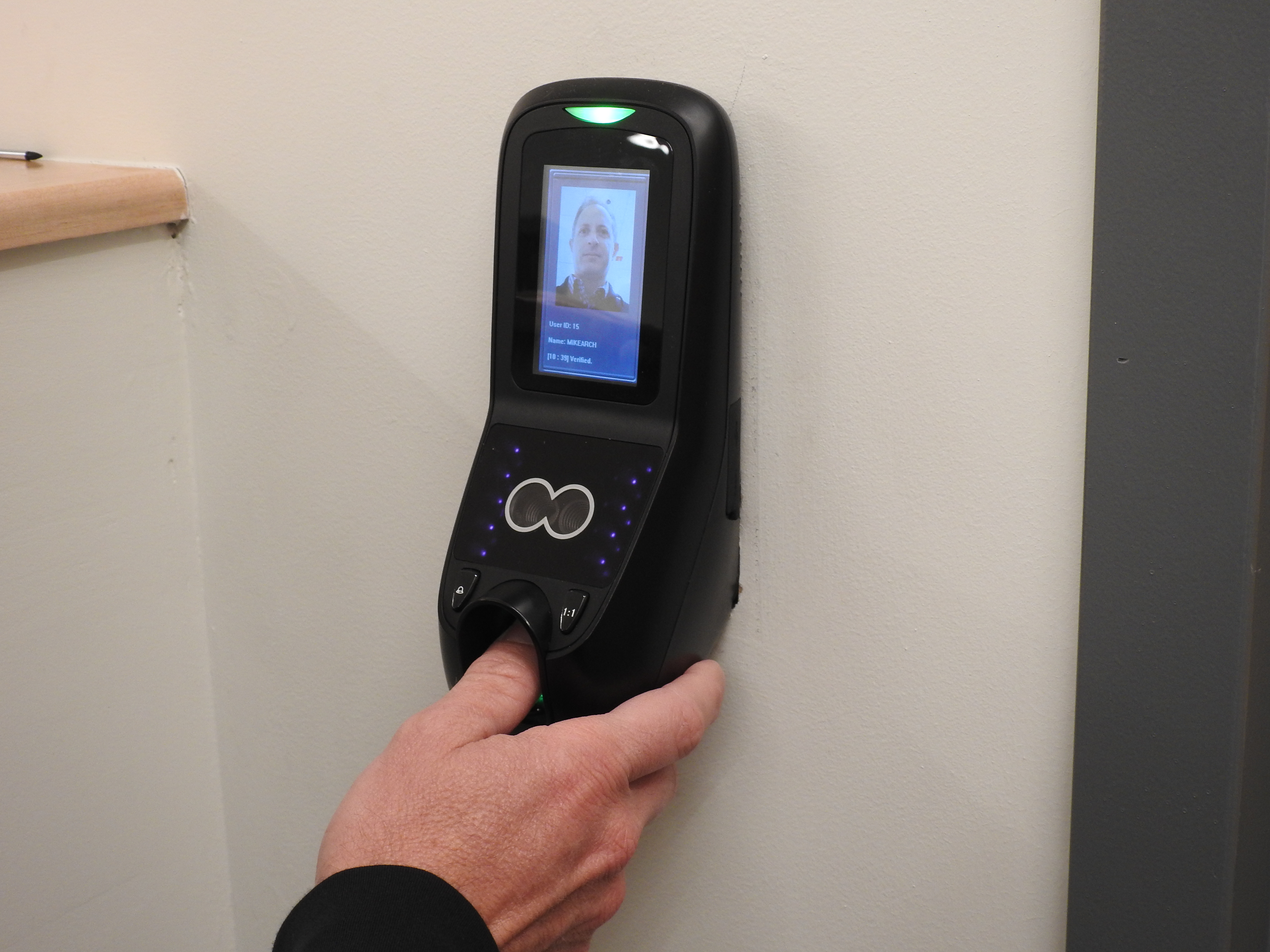 A thumbprint scanner placed on a wall next to a sealed doorway