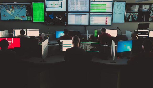 Room filled with monitors and technicians sitting at desks