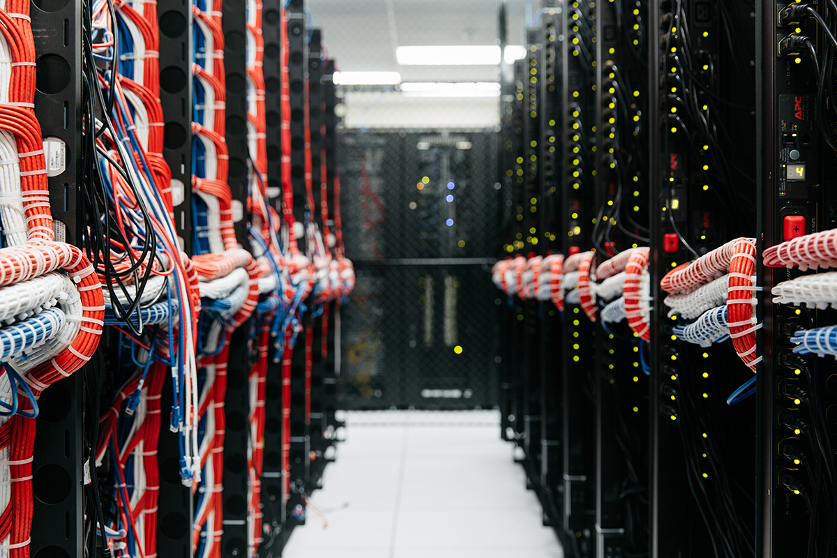 Two rows of server cabinets with multi-colored bundles of wiring.